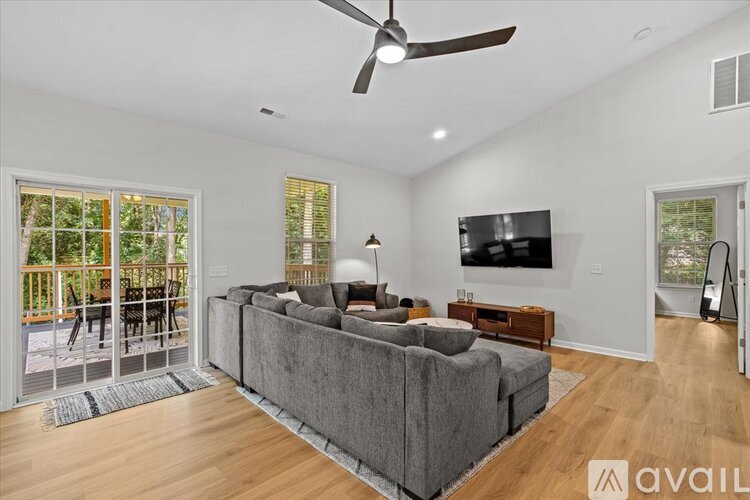 A living room with a grey couch and a television on the wall.