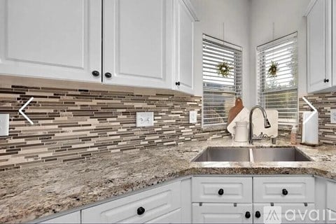 A kitchen with a stone backsplash and a sink.