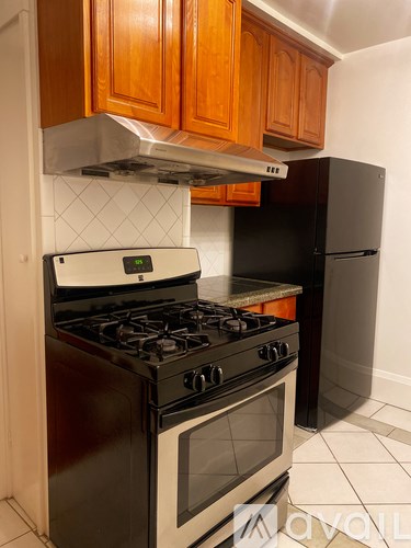 A kitchen with a black stove and wooden cabinets.