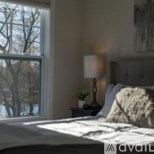 A bedroom with a large bed and a window overlooking a body of water.