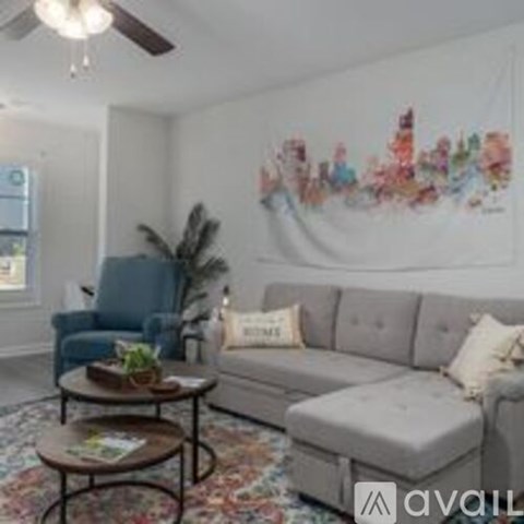 A living room with a grey couch, a blue chair, and a coffee table with a plant on it.