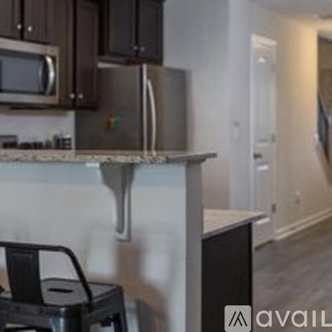 A kitchen with a microwave, oven, and a black trash can.