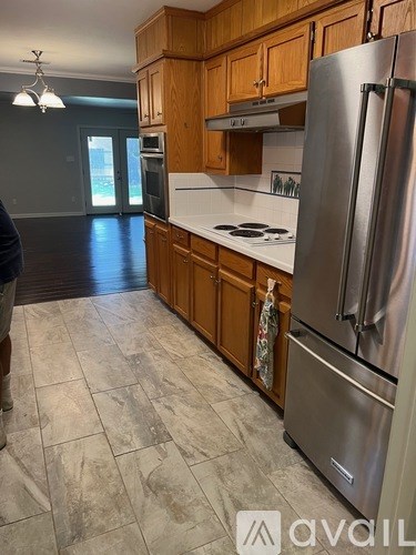 A kitchen with wooden cabinets and a stainless steel refrigerator.