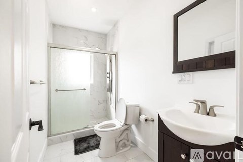 A bathroom with a toilet, sink, and mirror.