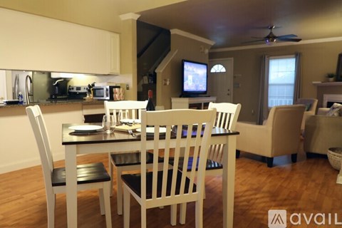 A dining room with a table set for two and a television in the background.