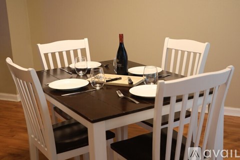A dining table with white chairs and a bottle of wine on it.
