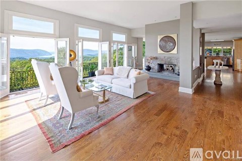 A living room with white furniture and a view of the mountains.