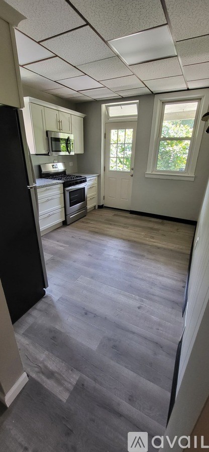 A kitchen with a black refrigerator and a window.