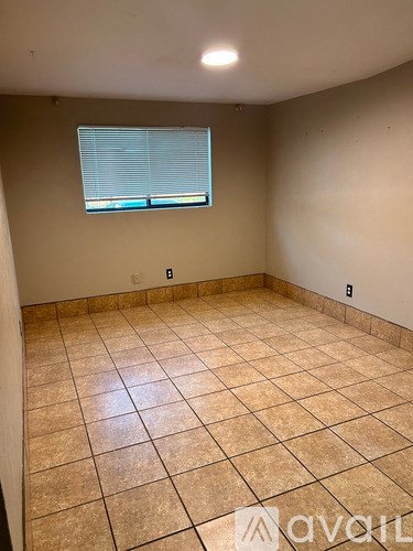 A room with tile flooring and a window with blinds.