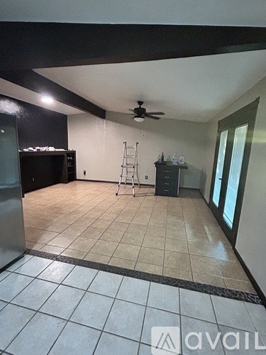 A room with a fan, a ladder, and a cabinet.