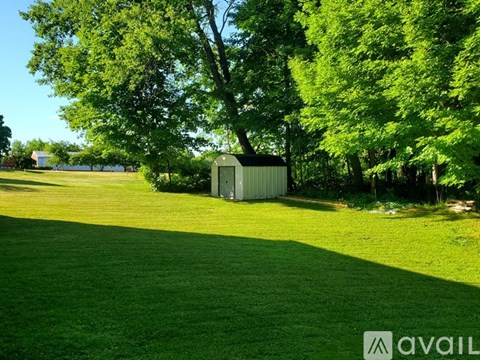 A green grass field with a small building and trees in the background.