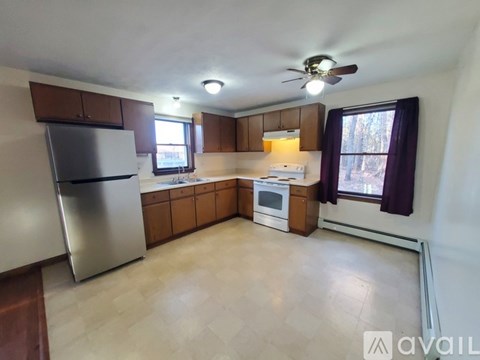 A kitchen with a refrigerator, oven, and a window with a view of trees.