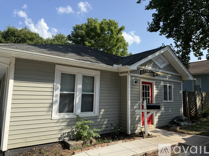 A small house with a red door and a grey siding.