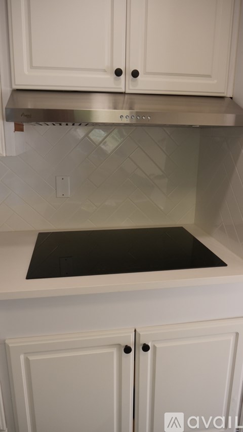 A kitchen with white cabinets and a stainless steel range hood.