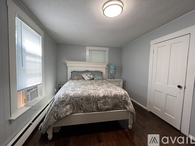 A bedroom with a bed, dresser, and window.