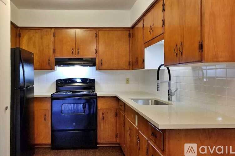 A kitchen with wooden cabinets and a black fridge.