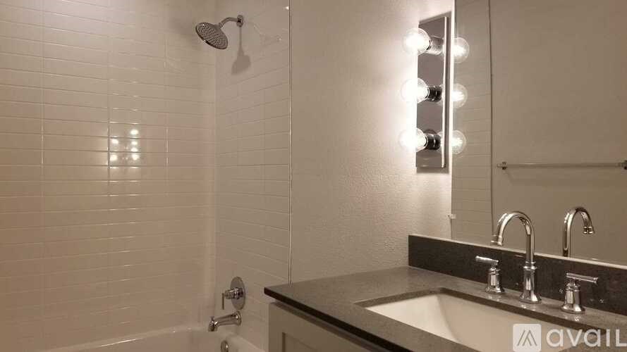 A bathroom with a sink, mirror, and shower.