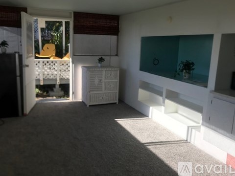 A room with a white cabinet and a window with a view of a yellow bird.