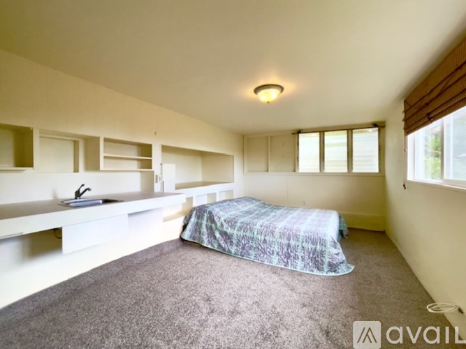 A bedroom with a bed, desk, and window.
