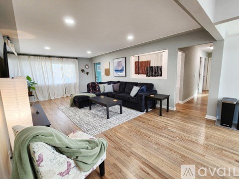 A living room with a black couch and a green blanket on it.