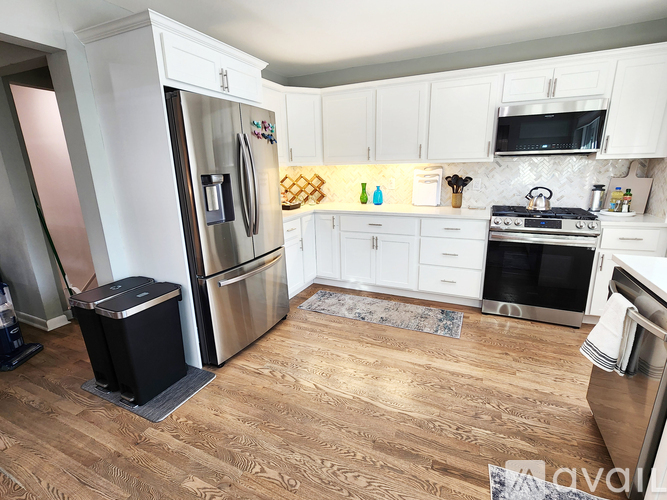 A kitchen with white cabinets and a wooden floor.