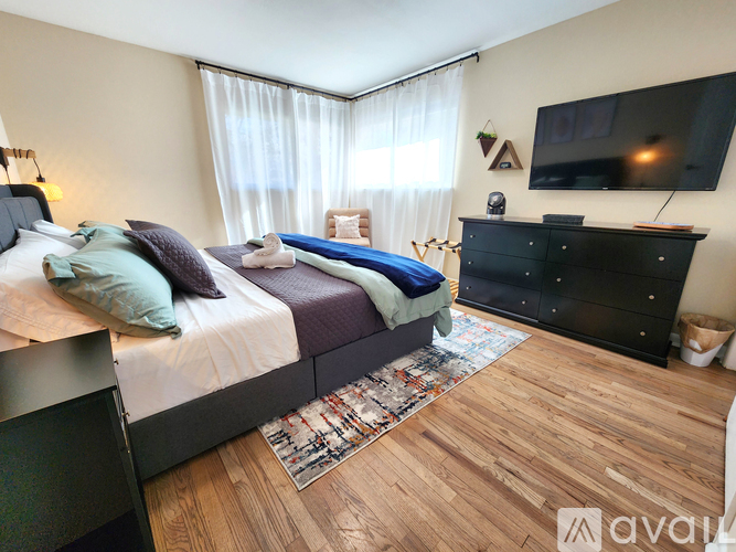 A bedroom with a large bed, a TV, and a wooden floor.