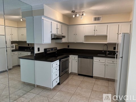 A kitchen with black countertops and white cabinets.