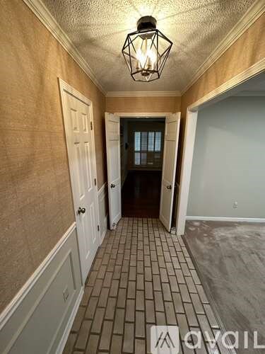 A hallway with a tiled floor and a light hanging from the ceiling.