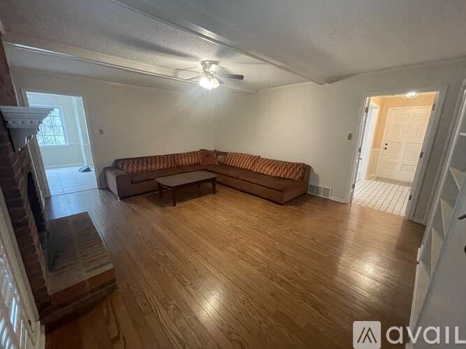 A living room with a brown couch and wooden floors.