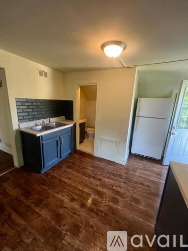 A kitchen area with a dark wood floor and a white fridge.