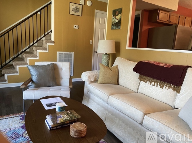 A living room with a white couch, a coffee table, and a staircase.