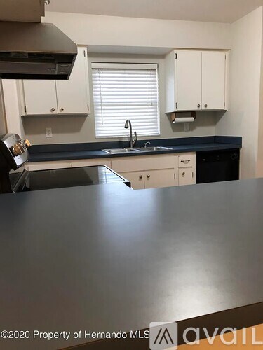 A kitchen with a black countertop and white cabinets.