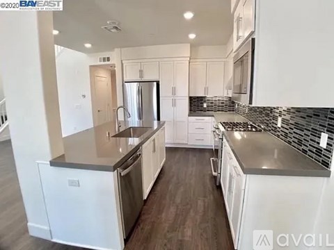 A modern kitchen with white cabinets and a stainless steel island.
