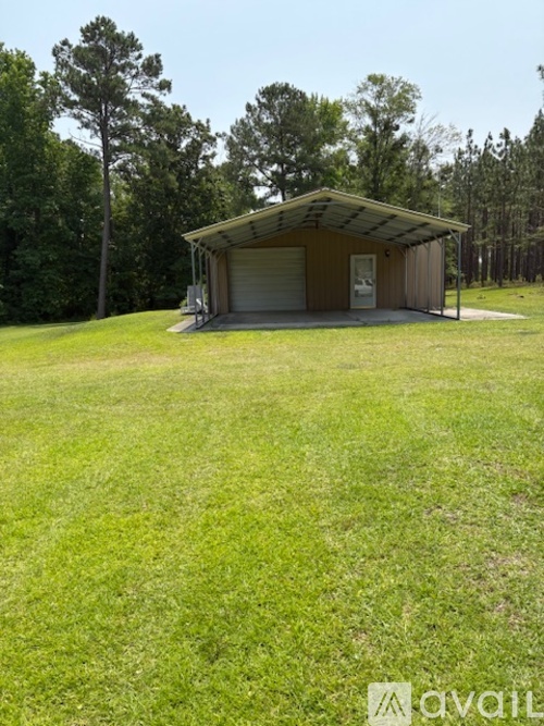 A small building with a covered porch sits in a grassy field.