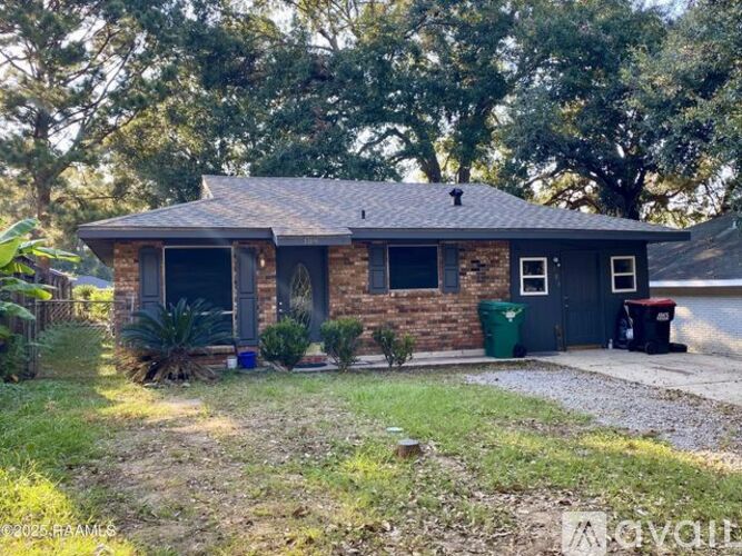A house with a gravel driveway and a green trash can.