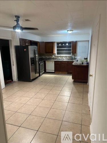 A kitchen with a black refrigerator and white appliances.