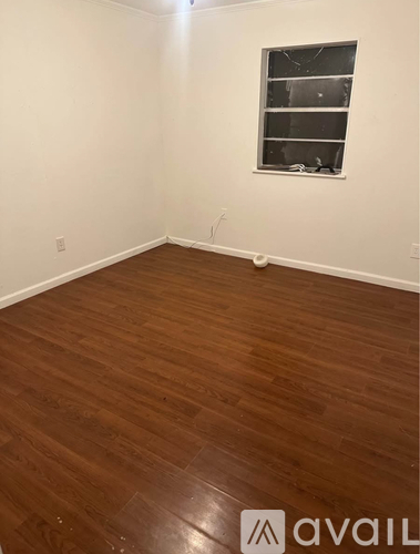 A room with wooden flooring and a window.