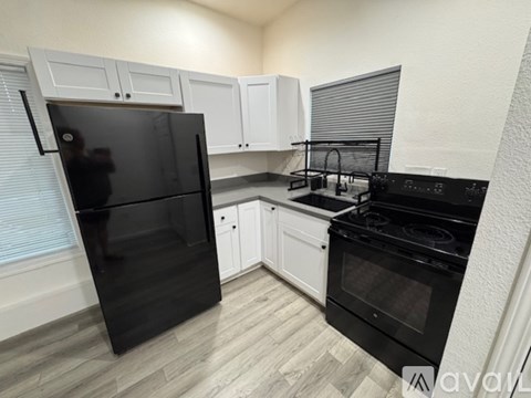A kitchen with black appliances and white cabinets.