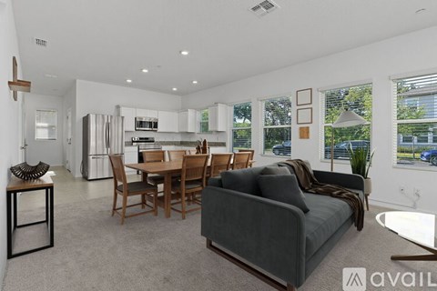 A modern living room with a grey couch and a dining table.