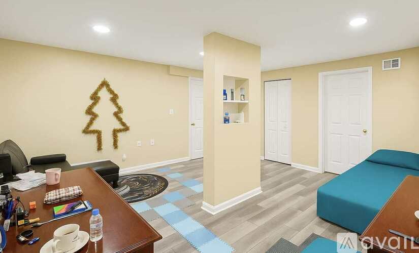 A room with a Christmas tree decoration on the wall and a blue couch.