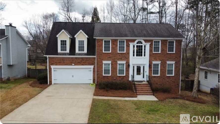 A two-story brick house with a white garage door and a white front door.