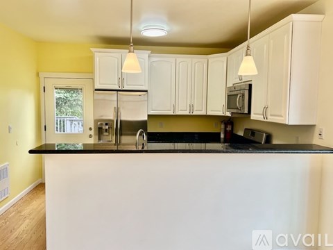 A kitchen with white cabinets and a black countertop.