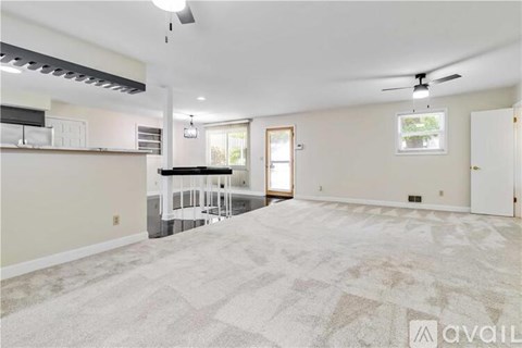 A spacious living room with a kitchen area in the background.