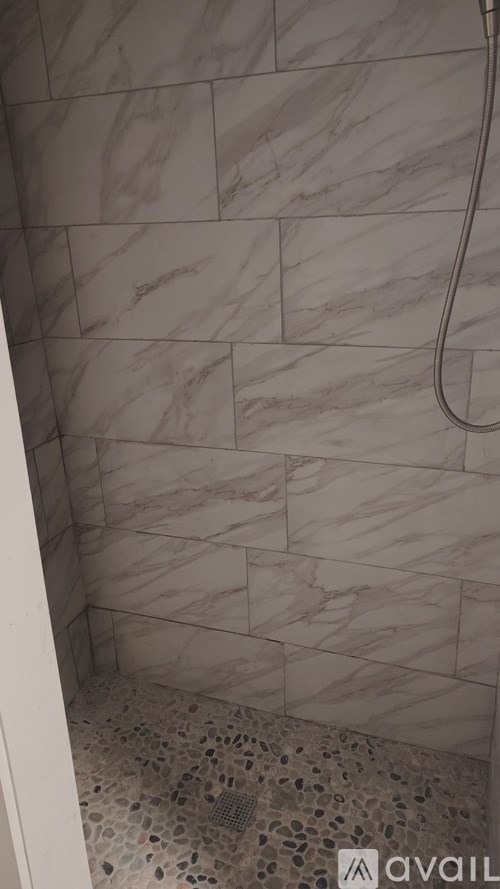 A shower with a marble tile wall and floor.