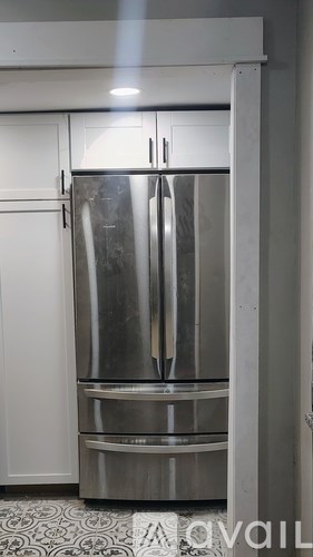 A stainless steel refrigerator with a freezer drawer is in a kitchen.