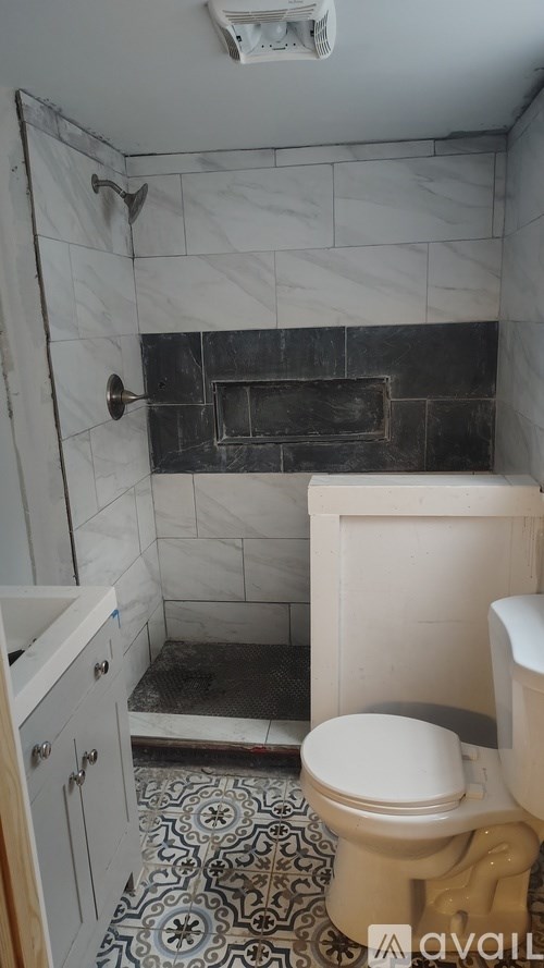 A bathroom with a toilet, a shower, and a tiled floor.