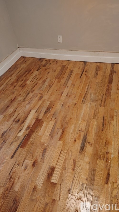 A room with wooden flooring and a white wall.