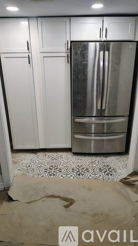 A kitchen with a stainless steel refrigerator and white cabinets.