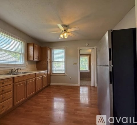 A kitchen with wooden cabinets and a black refrigerator.