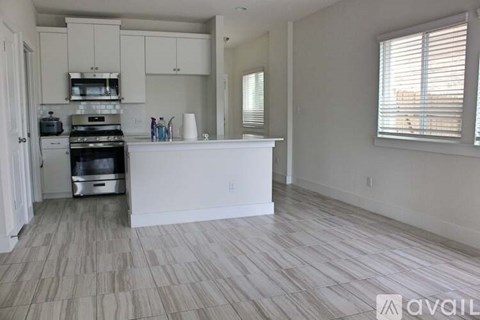 A kitchen with white cabinets and a wooden floor.